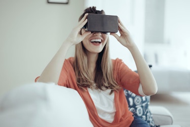  A young woman uses head-mounted virtual reality goggles. 