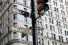 A traffic light in downtown NYC with the words Wall ST on the attached street signs.