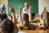 a group of children raising their hands in a classroom