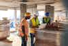 a group of men wearing hard hats and vests looking at a laptop