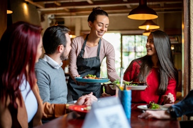  Happy server handing plates to restaurant customers. 