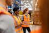 a group of women in orange vests in a warehouse