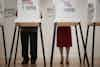 a man and woman standing in a room with voting boxes