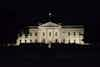 a white building with a flag on top with White House in the background