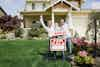 a family standing in front of a house holding a sign