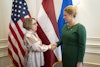 a woman shaking hands with another woman in front of flags