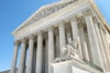 a statue of a man sitting on a chair in front of United States Supreme Court Building