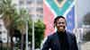 young man standing in front of building with South African flag painted on it