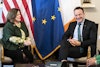 a man and woman sitting in chairs in front of flags