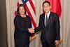 a man and woman shaking hands in front of flags