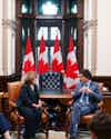 a man and woman sitting in chairs in front of flags